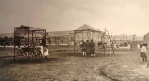 Newtongrange Welfare Park Children Centre/Playpark with children/adults in foreground and Primary school in background.