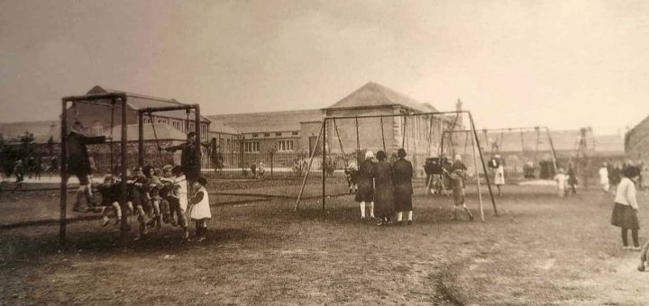 Newtongrange Welfare Park Children Centre/Playpark with children/adults in foreground and Primary school in background.